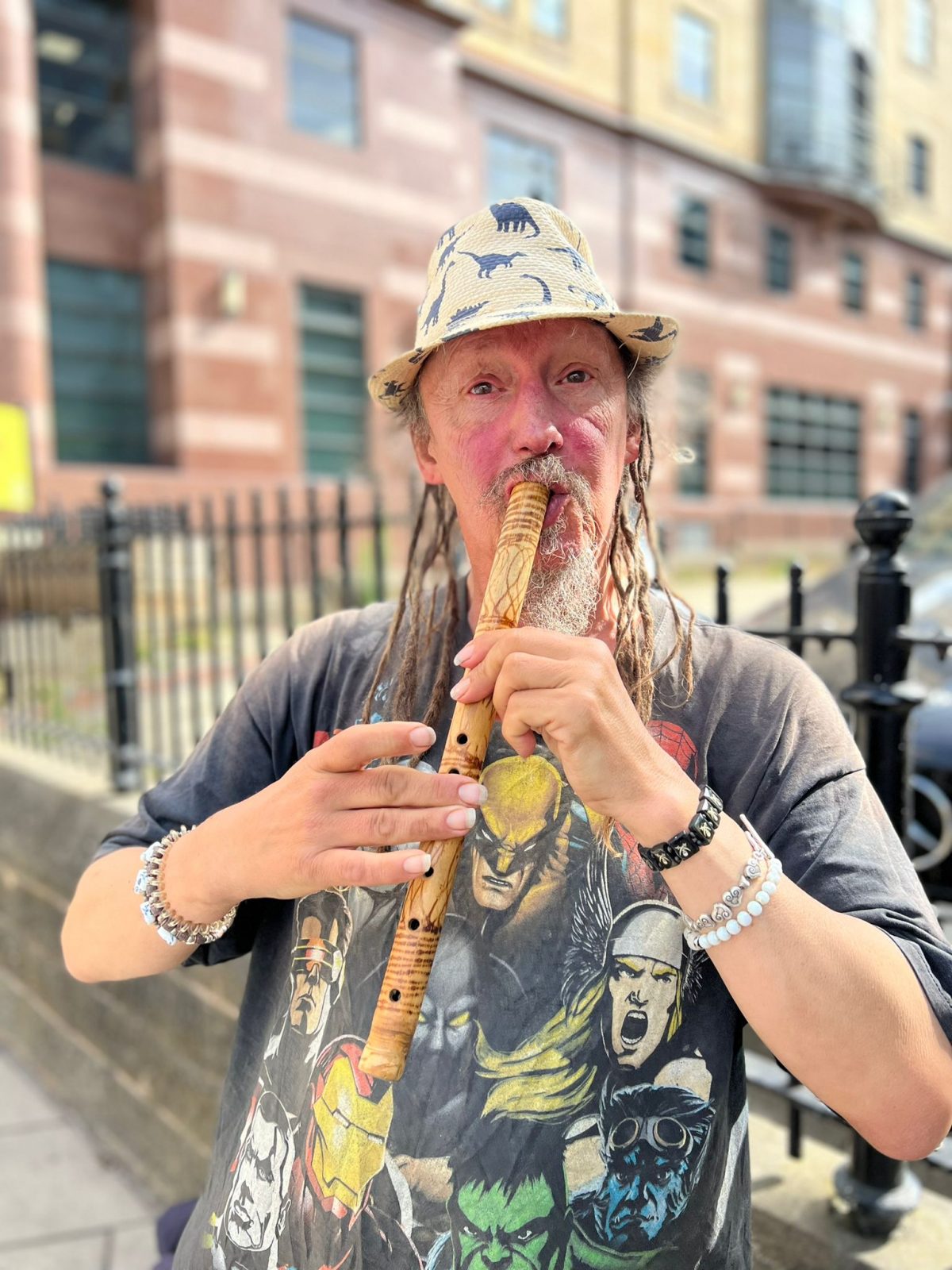 A busker holding a wooden flute in Leeds
